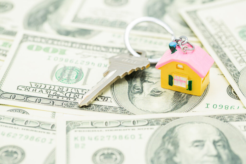 small house and keys on top of money