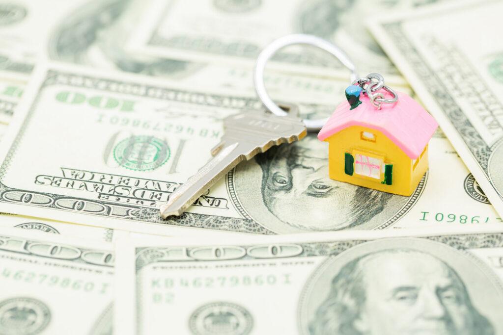small house and keys on top of money