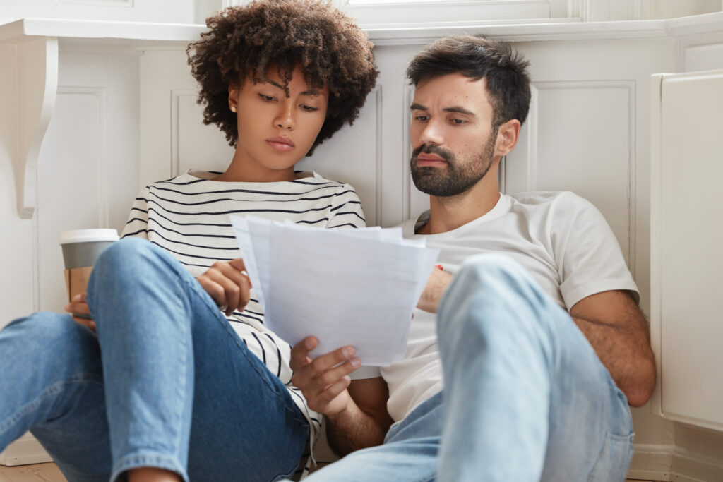 Young female and male managers work on executive task, speak about commercial affairs, cooperate for common task, feel relaxed on floor at balcony, work freelance, think on accounting report.